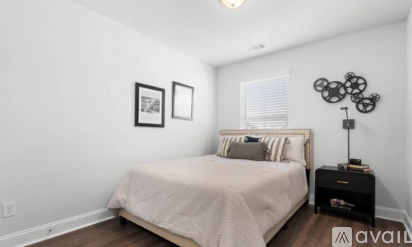 A bedroom with a bed, nightstand, and two picture frames on the wall.