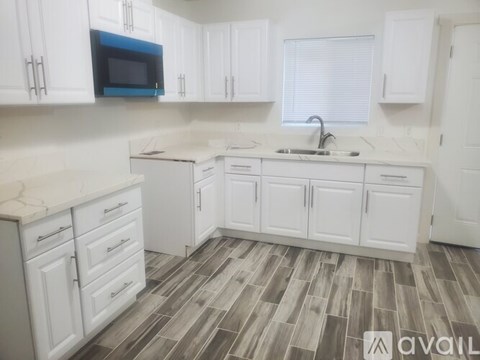 A kitchen with white cabinets and a blue microwave.