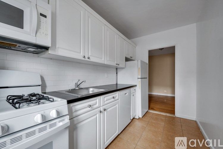 A kitchen with white cabinets and a black countertop.