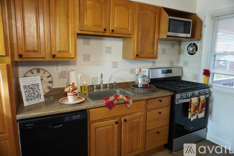 A kitchen with wooden cabinets and a black dishwasher.