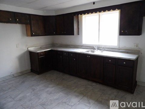 A kitchen with dark wood cabinets and a marble countertop.