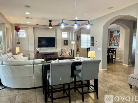 A living room with a white sofa, a television, and a dining table with chairs.