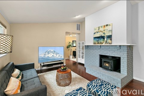 A living room with a grey couch, a fireplace, and a painting of a mountain on the wall.
