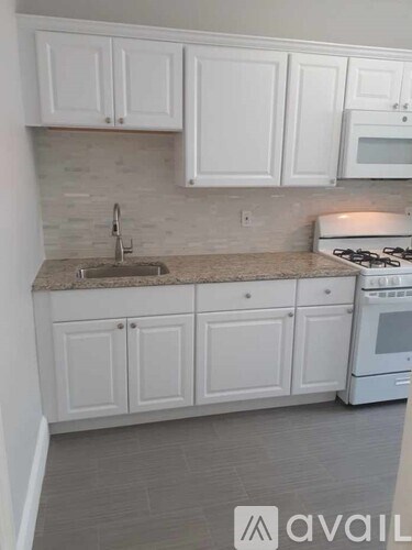 A kitchen with white cabinets and a granite countertop.