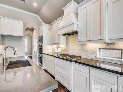 A kitchen with white cabinets and a marble countertop.