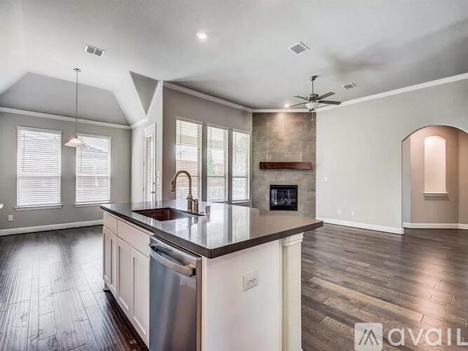 A modern kitchen with a large island and a stainless steel dishwasher.