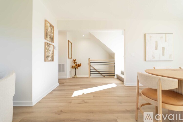 A room with a wooden floor and a white wall with a painting on it.