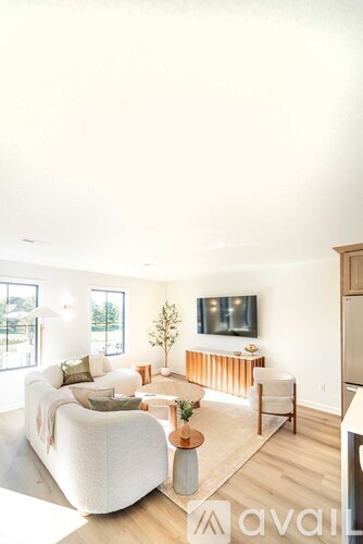 A living room with a white couch and a television on the wall.