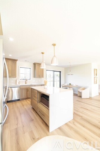 A modern kitchen with wooden floors and a white island.