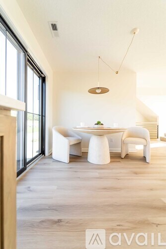 A modern dining room with a white table and chairs.