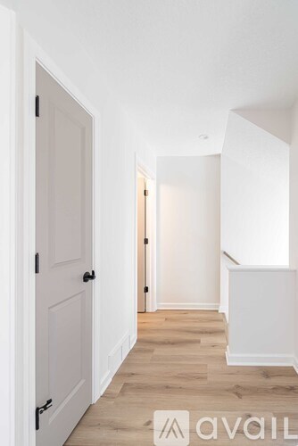 A hallway with a white door and wooden flooring.