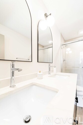 A white sink with a silver faucet and a round mirror above it.