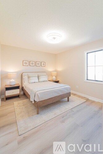 A bedroom with a bed, nightstands, and a window.