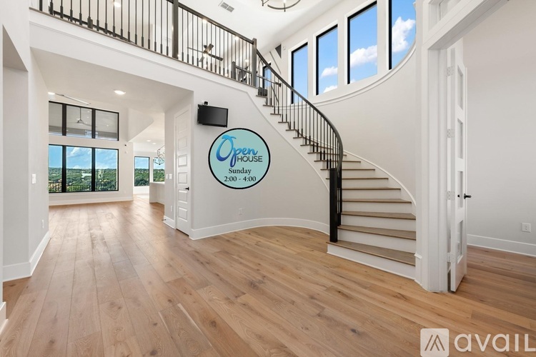 A spacious room with a staircase and a flat screen TV mounted on the wall.