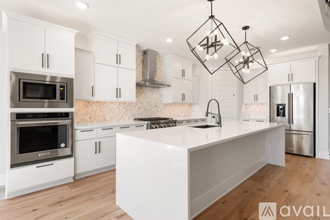 A modern kitchen with white cabinets and stainless steel appliances.