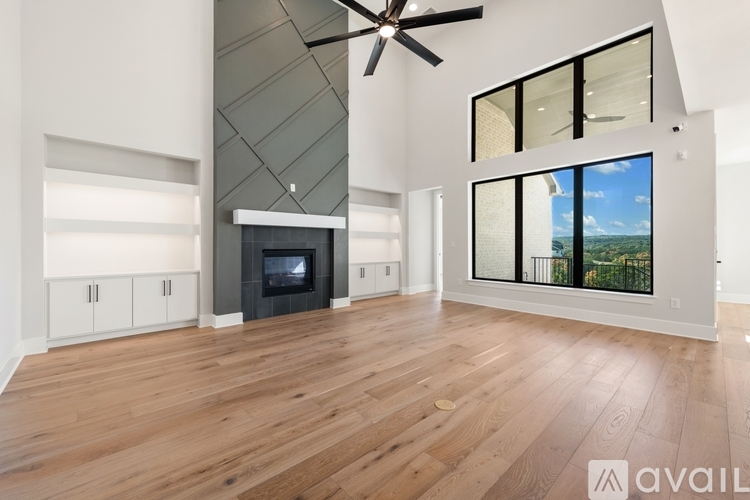 A spacious living room with a fireplace and a ceiling fan.