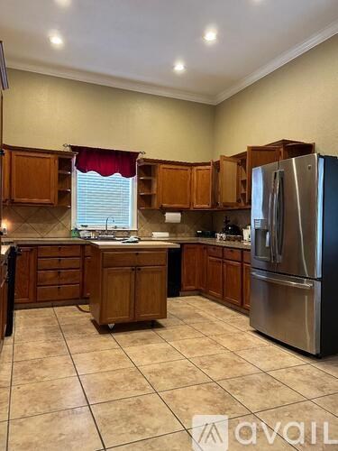 A kitchen with wooden cabinets and a stainless steel refrigerator.
