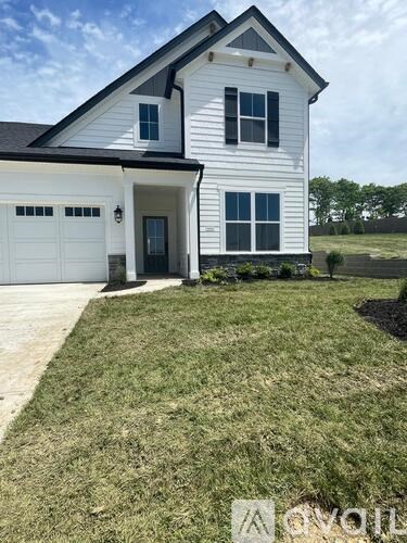 A white house with a black roof and a grey garage door.