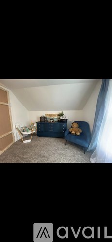 A living room with a blue sofa and a teddy bear on it.