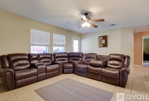 A living room with a large sectional sofa and a ceiling fan.