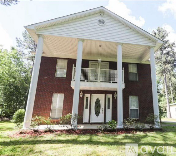 A red brick house with a white porch and pillars.