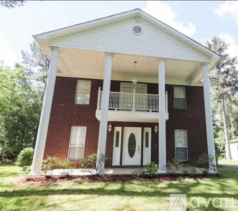 A red brick house with a white porch and pillars.