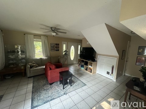 A living room with a red chair and a ceiling fan.