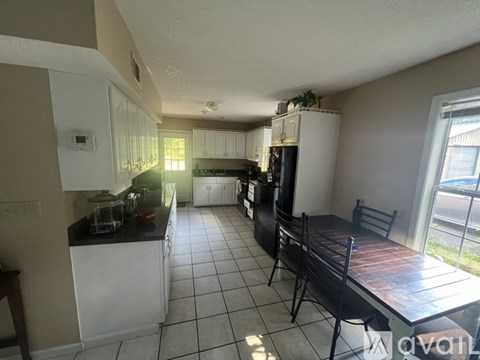 A kitchen with white cabinets and a black countertop.