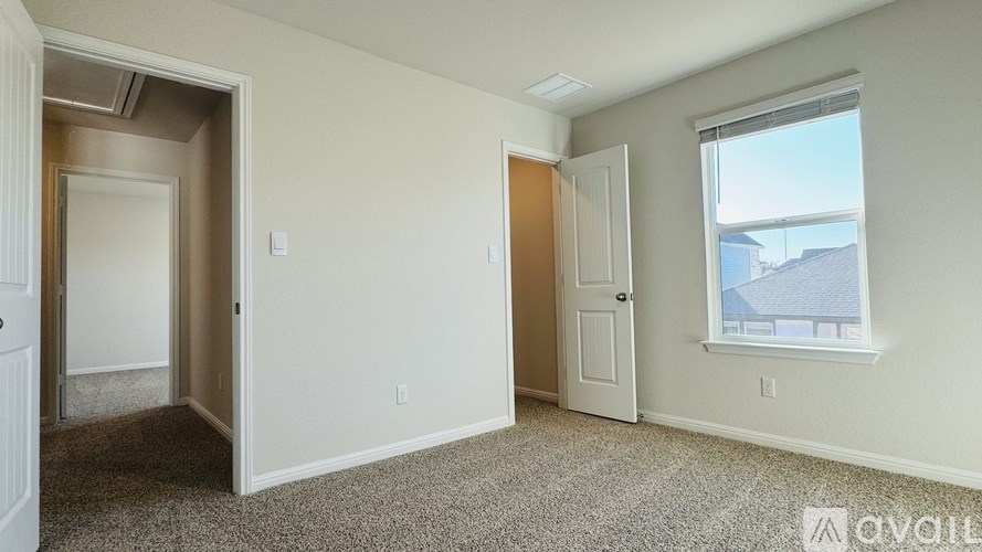A room with a carpeted floor and a window showing a blue house outside.