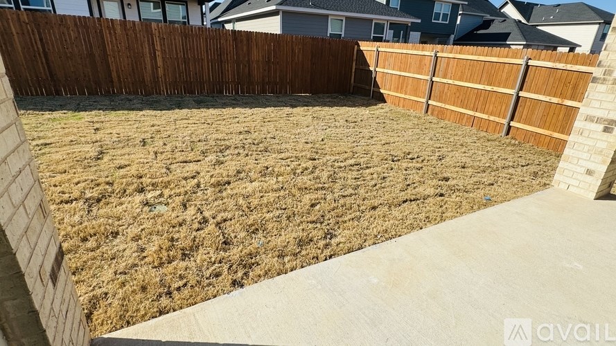 A backyard with a wooden fence and a concrete patio.