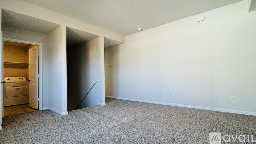 A spacious empty room with a carpeted floor and a doorway leading to another room.