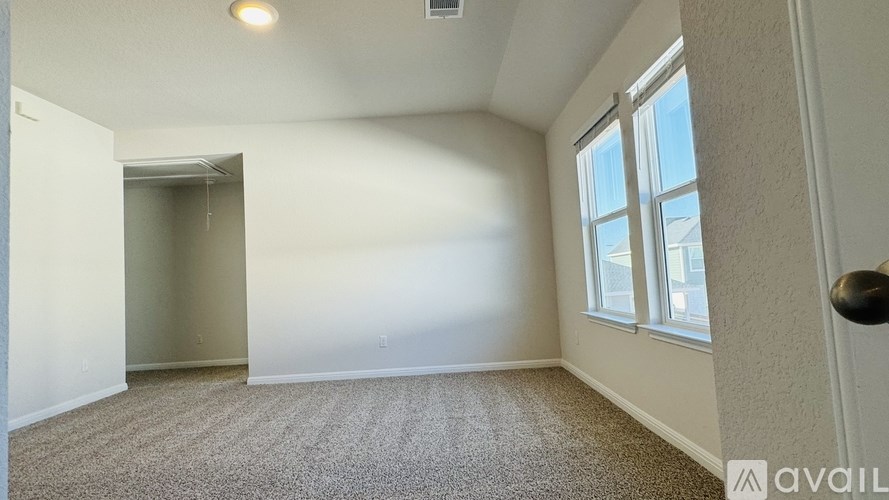 A room with a carpeted floor, a window, and a door.