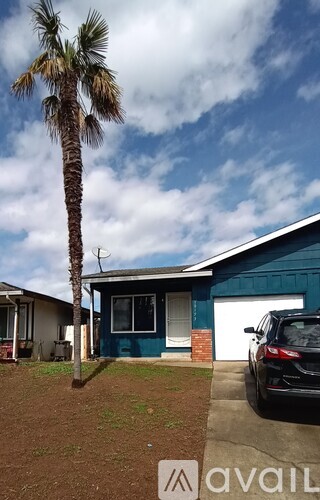 A house with a blue exterior and a palm tree in front.