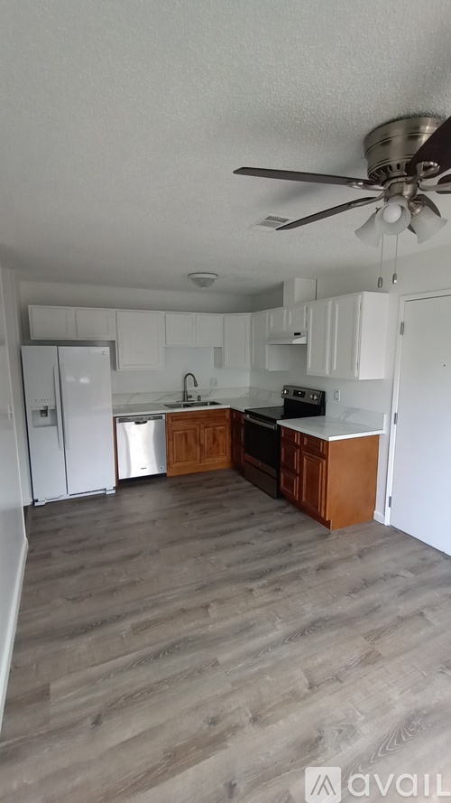 A kitchen with a fan on the ceiling and wooden flooring.