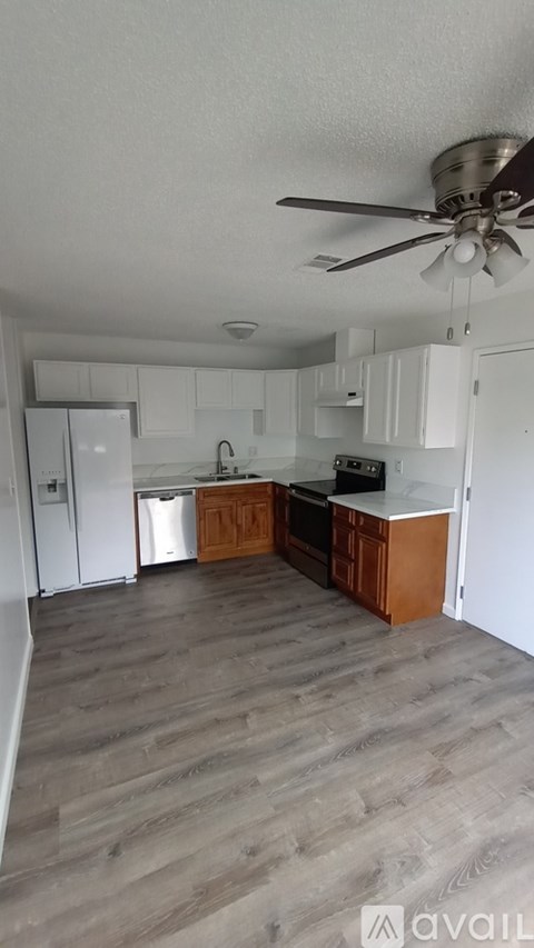 A kitchen with a fan on the ceiling and wooden flooring.