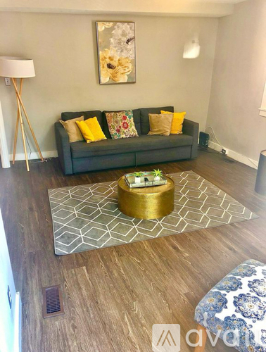 A living room with a grey couch, a gold coffee table, and a wooden floor.