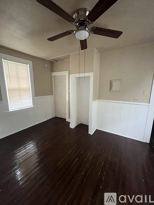 A room with a ceiling fan and wooden flooring.