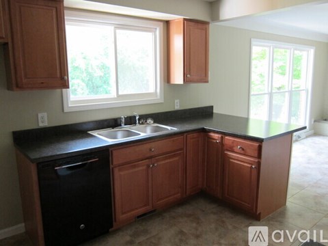 A kitchen with brown cabinets and a black countertop.
