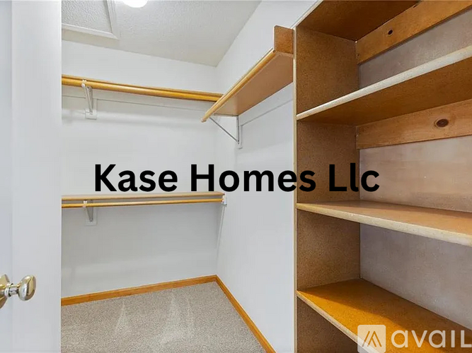 A room with a white wall and a wooden shelf with the text "Kase Homes LLC" on it.