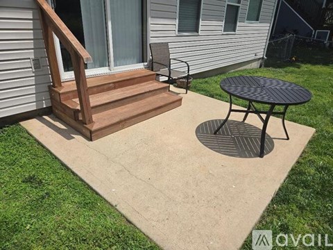 A patio with a table and a chair is in front of a house.
