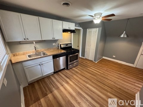 A kitchen with wooden floors and a stove top oven.