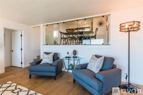 A living room with two blue couches and a glass table with a lamp.