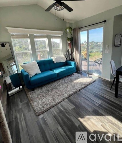A living room with a blue couch and a ceiling fan.