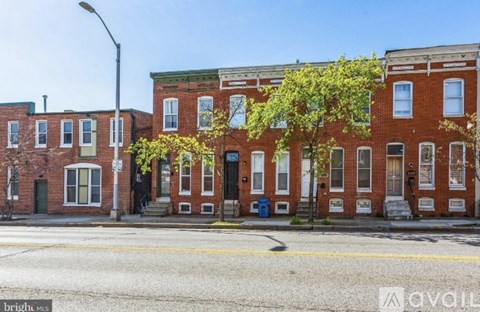A row of red brick townhouses with green doors and windows.
