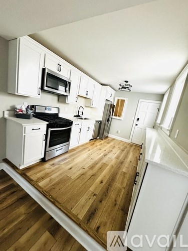 A kitchen with white cabinets and a wooden floor.
