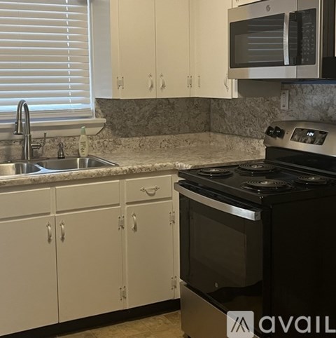 A kitchen with white cabinets and a black stove top oven.