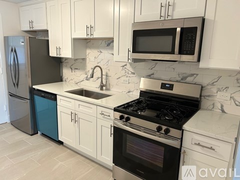 A kitchen with white cabinets and a black fridge.