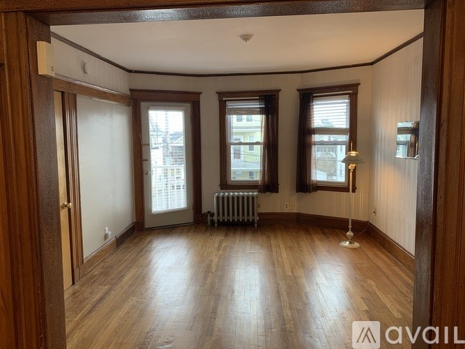 A room with wooden floors and three windows.