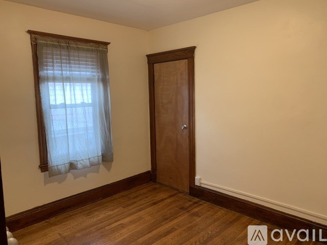 A room with a wooden door and a window with curtains.