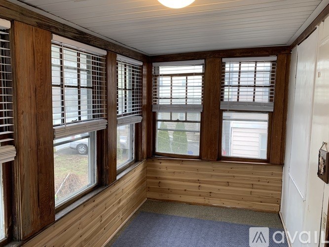 A room with wooden walls and a car visible through the window.